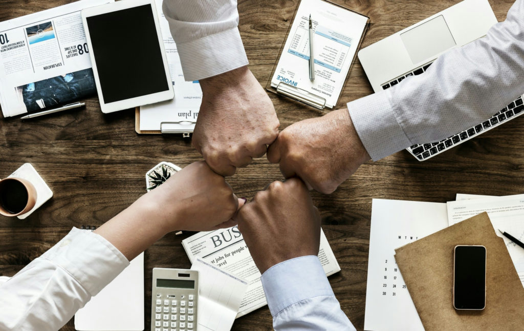 team fist bumping which represents working together