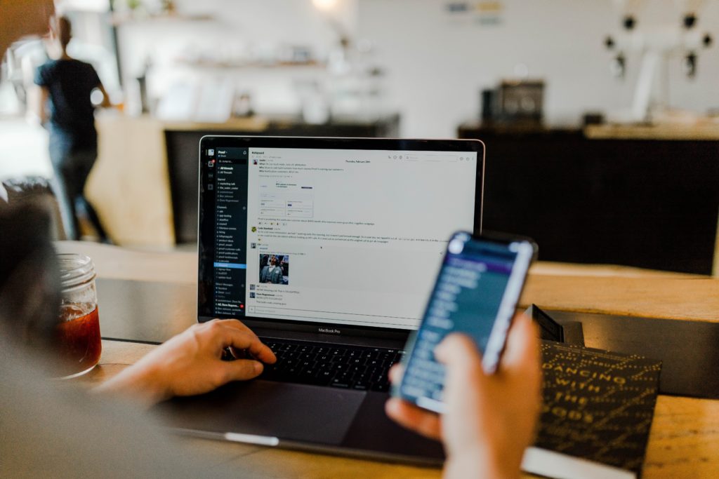 person using slack on his laptop and mobile phone