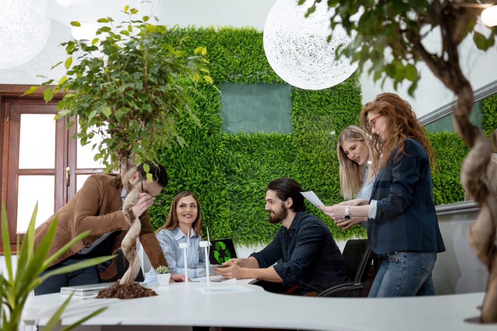 A team of smart qualified skilled young engineers discussing about the project of alternative energy with miniatures of windmill turbines at the table.